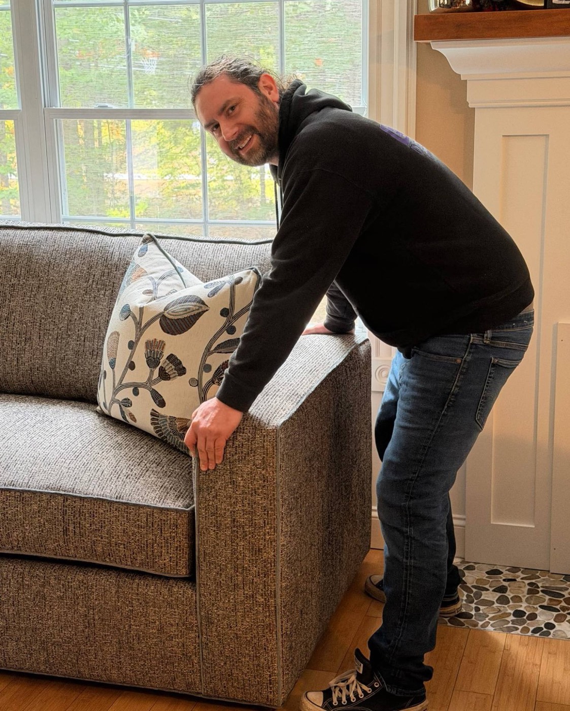 Kyle from EMK Deliveries adjusting an accent pillow on a delivered sofa
