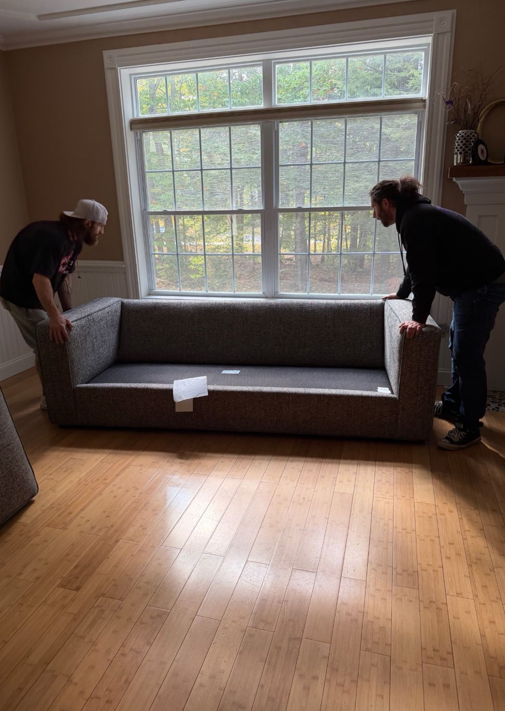 EMK crew carefully setting a new sofa in front of a living room window